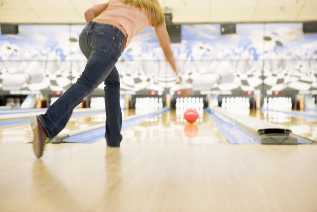 Picture shows a woman that is bowling in a bowling alley.