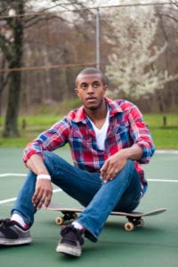 black man sitting on his skateboard in a ball park, stock photo, originally uploaded from Storyblocks with permission to ChiRhoDating.com