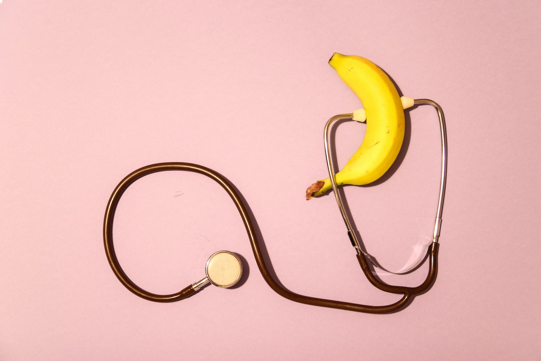a banana and a stethoscope on a pink surface