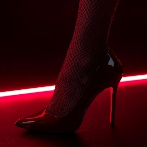 Red high heel with net stockings, symbolizing sultry allure and feminine power.