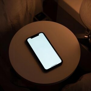 Empty phone screen on nightstand showing absence of messages, representing emotional silence