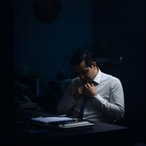 Stressed successful man alone at night, showing emotional exhaustion and conflict.