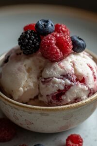 closeup image of vanilla berry ice cream topped with fresh berries,