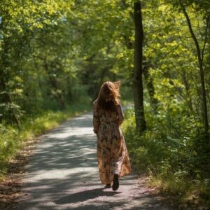 woman in a floral dress walking on a path in the forest,